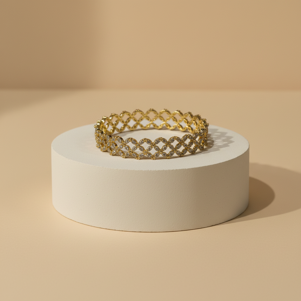 A gold-tone interlocking lattice bracelet displayed on a round white pedestal against a warm beige studio background.